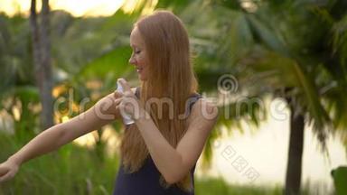 一位美丽的年轻女子用防蚊剂喷在皮肤上的超慢镜头。 一片热带